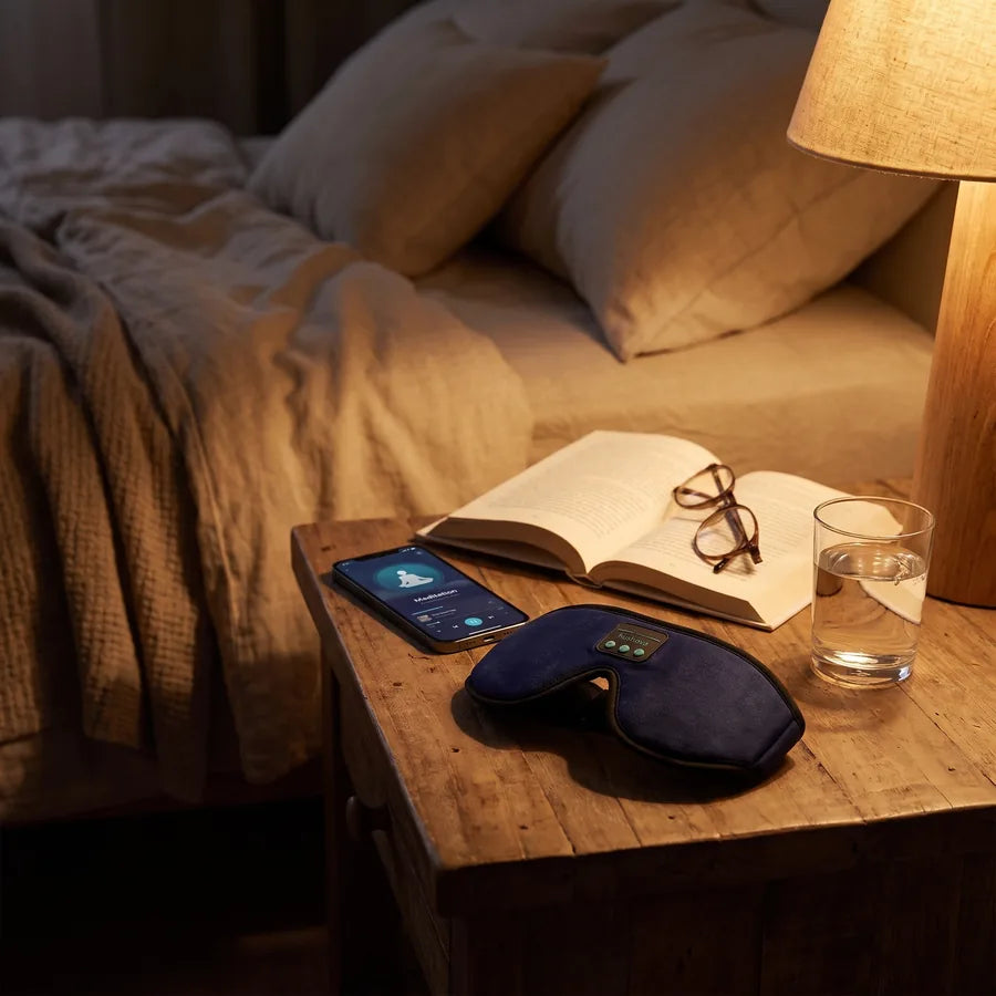 Hushova navy sleep mask on a nightstand at night